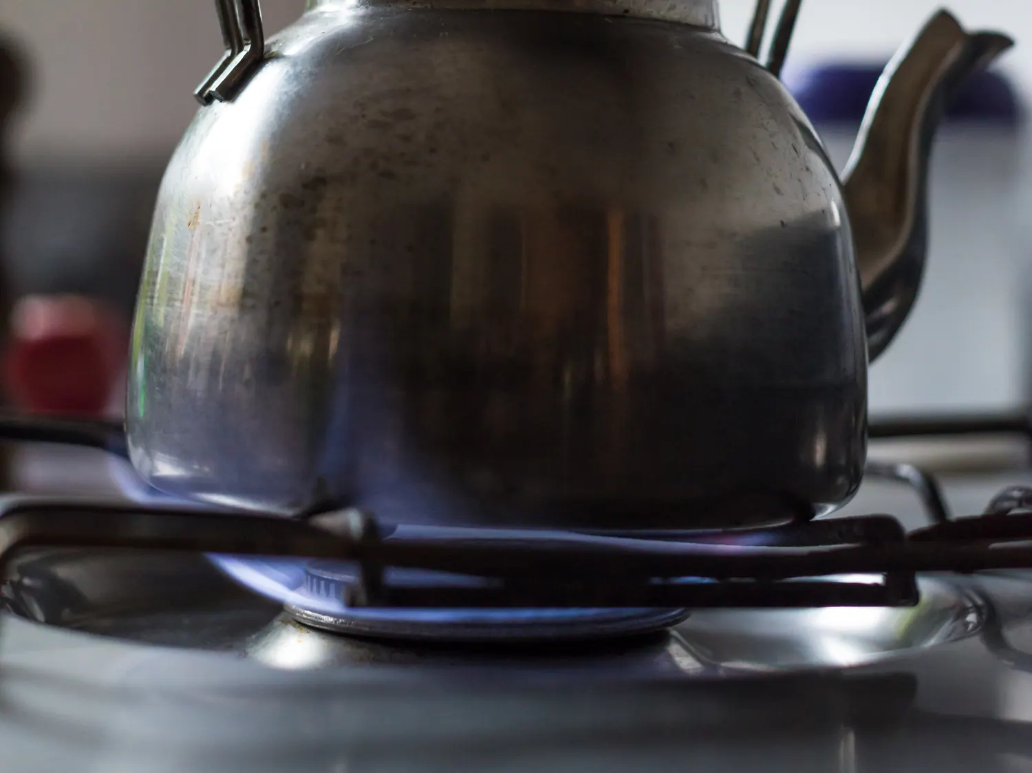 A kettle heating over the blue flame of a gas burner